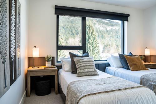 two beds in a room with a window at The Big Deck by Revelstoke Vacations in Revelstoke