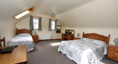 a bedroom with two beds and a desk and windows at Fishermans Village with Sea Views in Downings