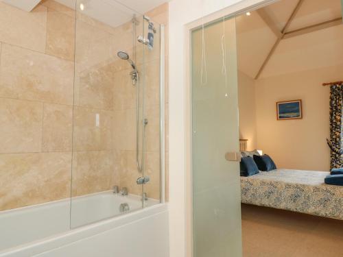 a bathroom with a shower and a tub and a bed at Kestrel, 19 Dartmouth Green in Totnes