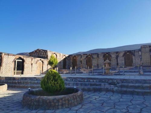 einen Innenhof eines Backsteingebäudes mit einem Busch davor in der Unterkunft Little Petra Heritage Village in Wadi Musa