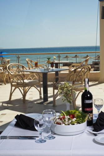 a table with a bowl of salad and a bottle of wine at Shams Prestige Abu Soma (Adults Only) in Hurghada