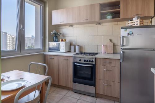 a kitchen with a stainless steel refrigerator and a table at Apartament Kremowy - blisko morza i Sopotu in Gdańsk