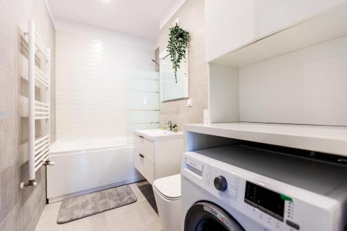 uma casa de banho branca com uma máquina de lavar roupa em Vanilla Apartment - Pipera em Bucareste