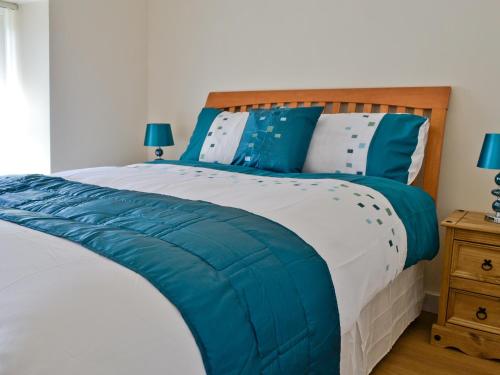 een bed met blauwe en witte lakens en kussens bij Ty Capel Gosen in Trevor