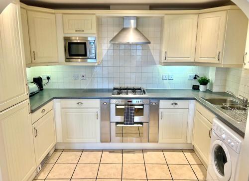 貝辛斯托克的住宿－2 Bed Serviced Apartment with Balcony, Free Parking, Wifi & Netflix in Basingstoke，厨房配有白色橱柜和炉灶烤箱。