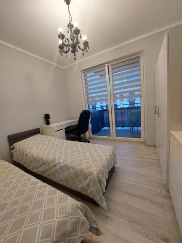 a bedroom with two beds and a desk and a chandelier at Apartament Ania in Świnoujście