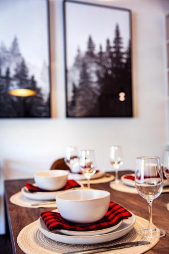 a wooden table with plates and bowls and wine glasses at Monashee Sunshine - Condo with Private Hot Tub in Revelstoke