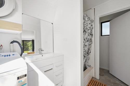 une cuisine blanche avec un évier et un miroir dans l'établissement Pihanga Cottage - Kuratau Bach, à Kuratau