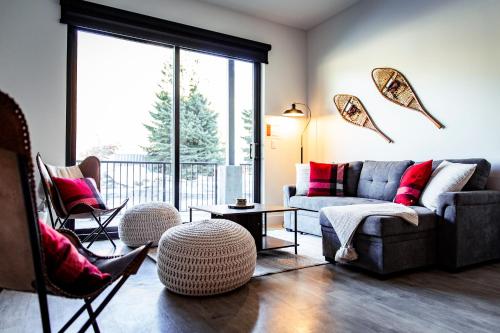 a living room with a couch and chairs and a large window at Monashee Sunshine - Condo with Private Hot Tub in Revelstoke