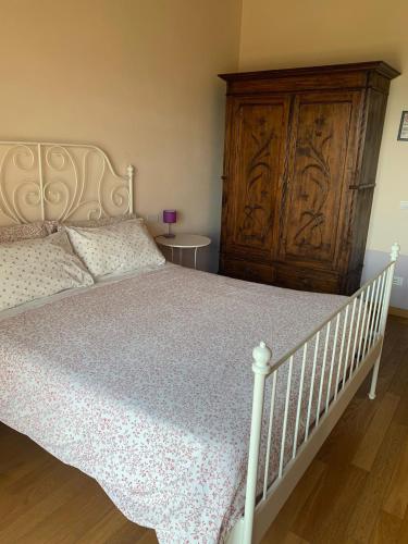 a bedroom with a white bed and a wooden cabinet at Agriturismo Il Filare in Neviano degli Arduini