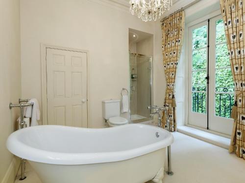 uma banheira branca na casa de banho com uma janela em Lumsdale House em Matlock
