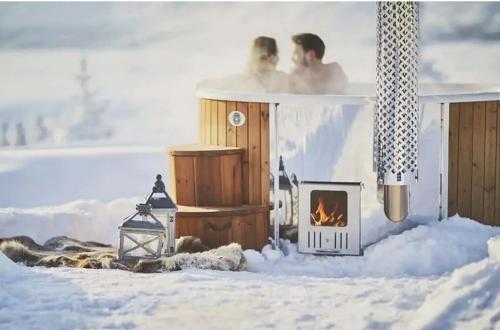 two people in a hot tub with a fireplace at Yukon River Farm in Whitehorse