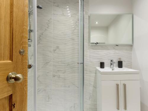 a shower with a glass door next to a sink at Rimmers Farmhouse in Wichenford