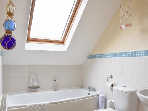 a bathroom with a white tub and a window at Riverside Cottage in Whitby