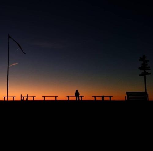 a person sitting on a bench in front of the sunset at Lägenhet Yvonne in Gränna