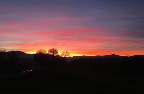 a sunset with trees and mountains in the background at Agriturismo Il Filare in Neviano degli Arduini