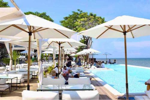 a pool with white umbrellas and people sitting around it at Mountain View resort-style Condominium in Hua Hin