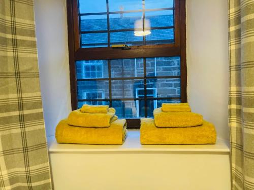 dwa ręczniki siedzące na parapecie przed oknem w obiekcie Trawsfynydd Stone Cottage w mieście Trawsfynydd