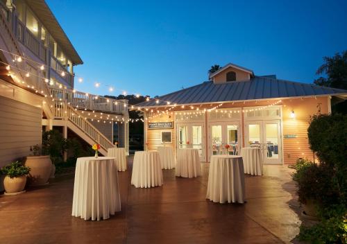 a set of white tables in front of a building with lights at Avila Lighthouse Suites in Avila Beach