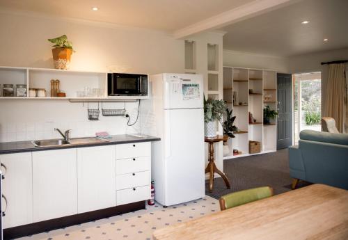 a kitchen with a white refrigerator and a table at Lawrence creek cottage Bruny Island in Simpsons Bay