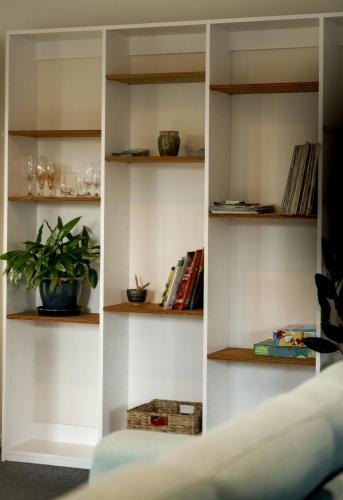 a book shelf with books and a plant on it at Lawrence creek cottage Bruny Island in Great Bay