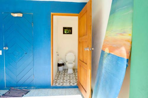 Hostel Esperanza في بافونيس: حمام به مرحاض وجدار أزرق
