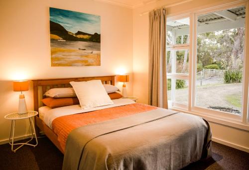 a bedroom with a bed and a large window at Lawrence creek cottage Bruny Island in Great Bay