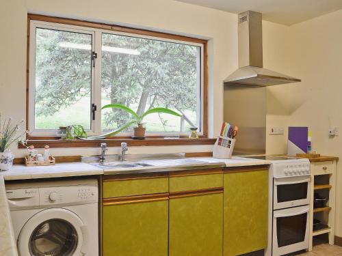 een keuken met een wastafel en een wasmachine bij Crubisdale in Blairmore