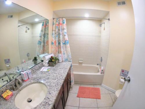 a bathroom with a sink and a tub and a mirror at Orlando Vacation Apartment 3919 in Orlando