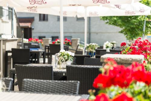 un patio al aire libre con mesas y sillas con flores rojas en Hotel Krone, en Niederstotzingen