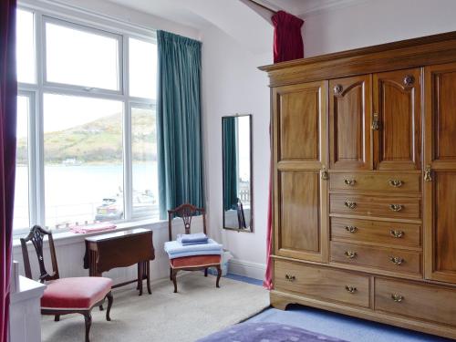 a bedroom with a large wooden dresser and a large window at The Shieling in Lochranza