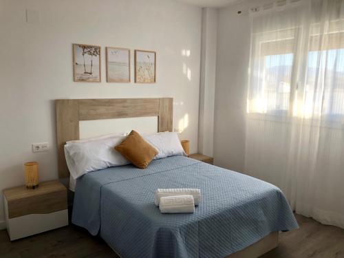 um quarto com uma cama com um cobertor azul e uma janela em Apartamento Aguacate beach playa Granada em Motril
