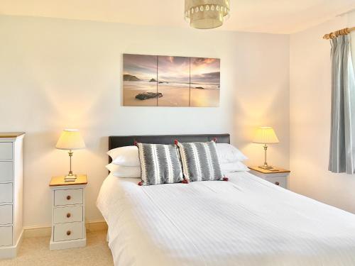 a bedroom with a large white bed with two lamps at Harvest Cottage in Padstow
