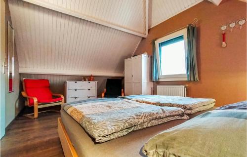 1 dormitorio con 2 camas y silla roja en Stunning Home In Wolphaartsdijk With Kitchen, en Wolphaartsdijk