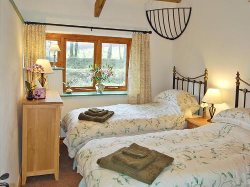 een slaapkamer met 2 bedden en een raam bij The Stables in Bodmin