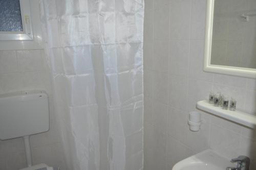 a white bathroom with a shower curtain and a toilet at Junction studios in Skiathos Town