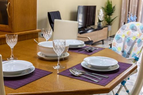 a wooden table with plates and silverware on it at Johnny's Three Bedroom Apartment in Nafplio