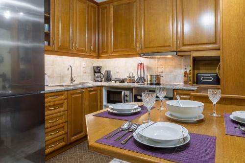 a kitchen with wooden cabinets and a table with plates and wine glasses at Johnny's Three Bedroom Apartment in Nafplio
