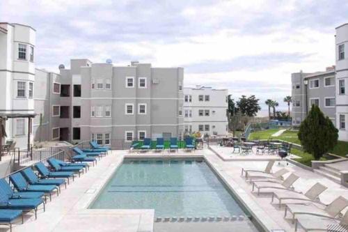 une piscine avec des chaises longues et un bâtiment dans l'établissement Departamento en 1er piso 2 bdr 2bath tezal, à Cabo San Lucas