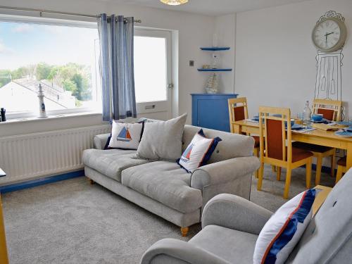 a living room with a couch and a table and a clock at Galleons Reach in Instow