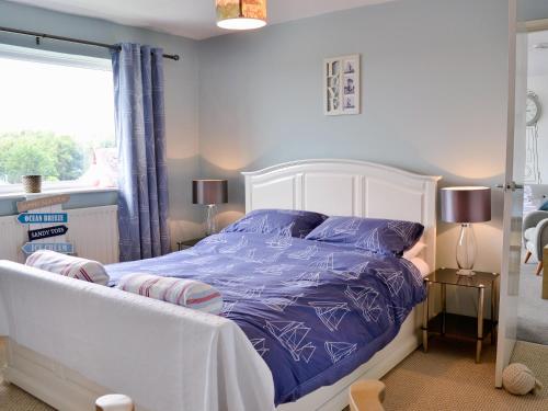 a bedroom with a bed with purple sheets and a window at Galleons Reach in Instow