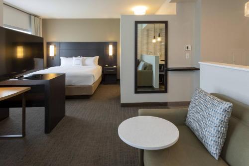 a hotel room with a bed and a table and a chair at Residence Inn Minneapolis Maple Grove/Arbor Lakes in Maple Grove