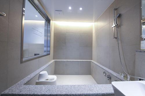 a bathroom with a tub and a sink and a mirror at Asherah Villa d' aqua Hotel in Gimhae