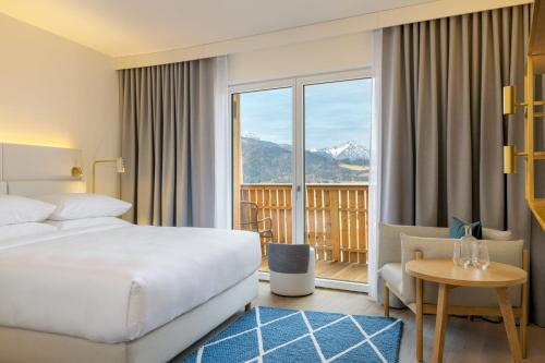a hotel room with a bed and a balcony at Caro & Selig, Tegernsee, Autograph Collection in Tegernsee