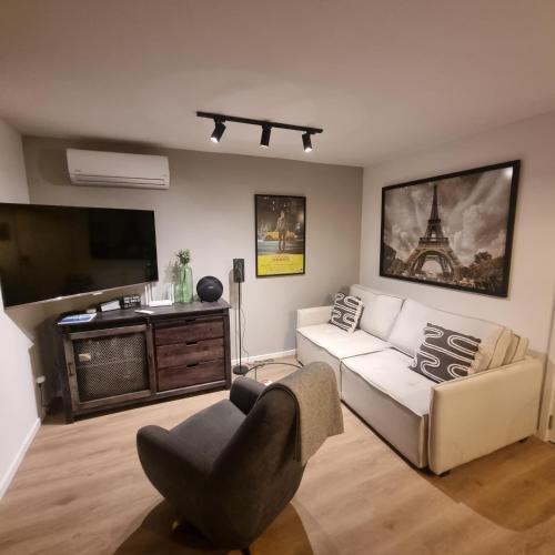 sala de estar con sofá, TV y silla en Exclusivo Penthouse en Cordon Soho con Parking y STARPLUS incluidos en Montevideo