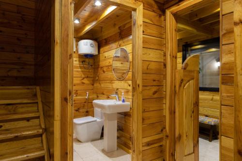 a bathroom in a log cabin with a sink and a toilet at أكواخ غيم ومطر in Al Hada