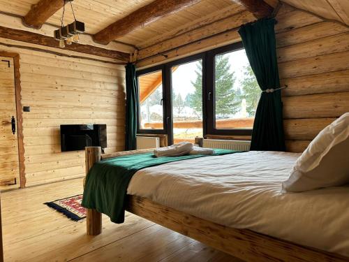 a bedroom with a bed in a log cabin at Yanis Chalet Dorna in Vatra Dornei