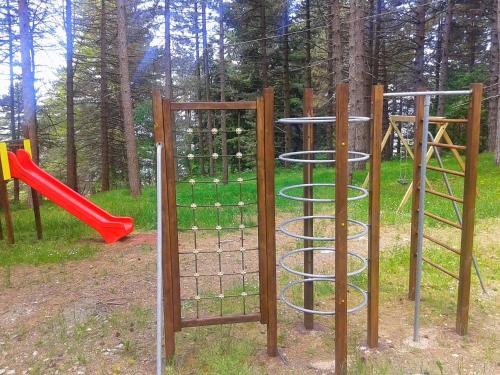 a playground with two swings and a red slide at Villaggio Barilari in Minucciano