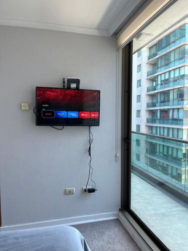 uma televisão de ecrã plano pendurada numa parede ao lado de uma janela em Apart360 em Concepción