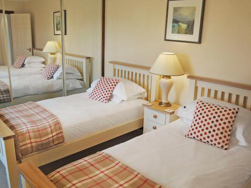 a bedroom with two beds and a lamp and a mirror at Prideaux Cottage in Luxulyan